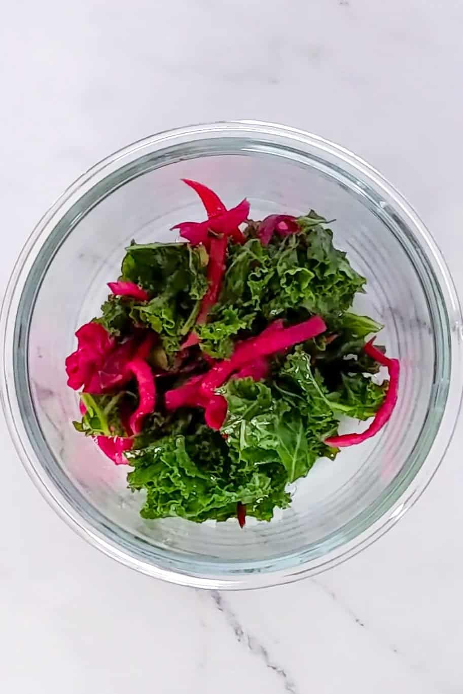 Vibrant kale salad with sliced radish, showcasing fresh greens and colorful, healthy ingredients.