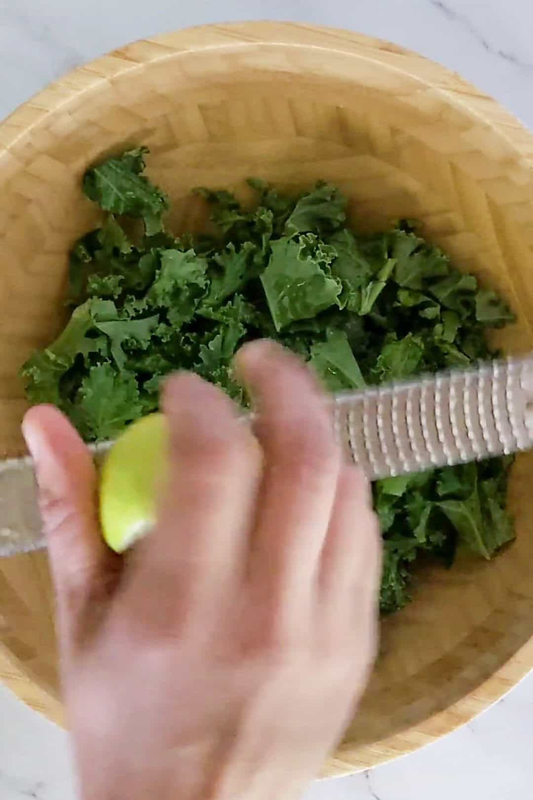 Fresh kale and lime zest prepare for a vibrant, healthy meal in a rustic bowl.