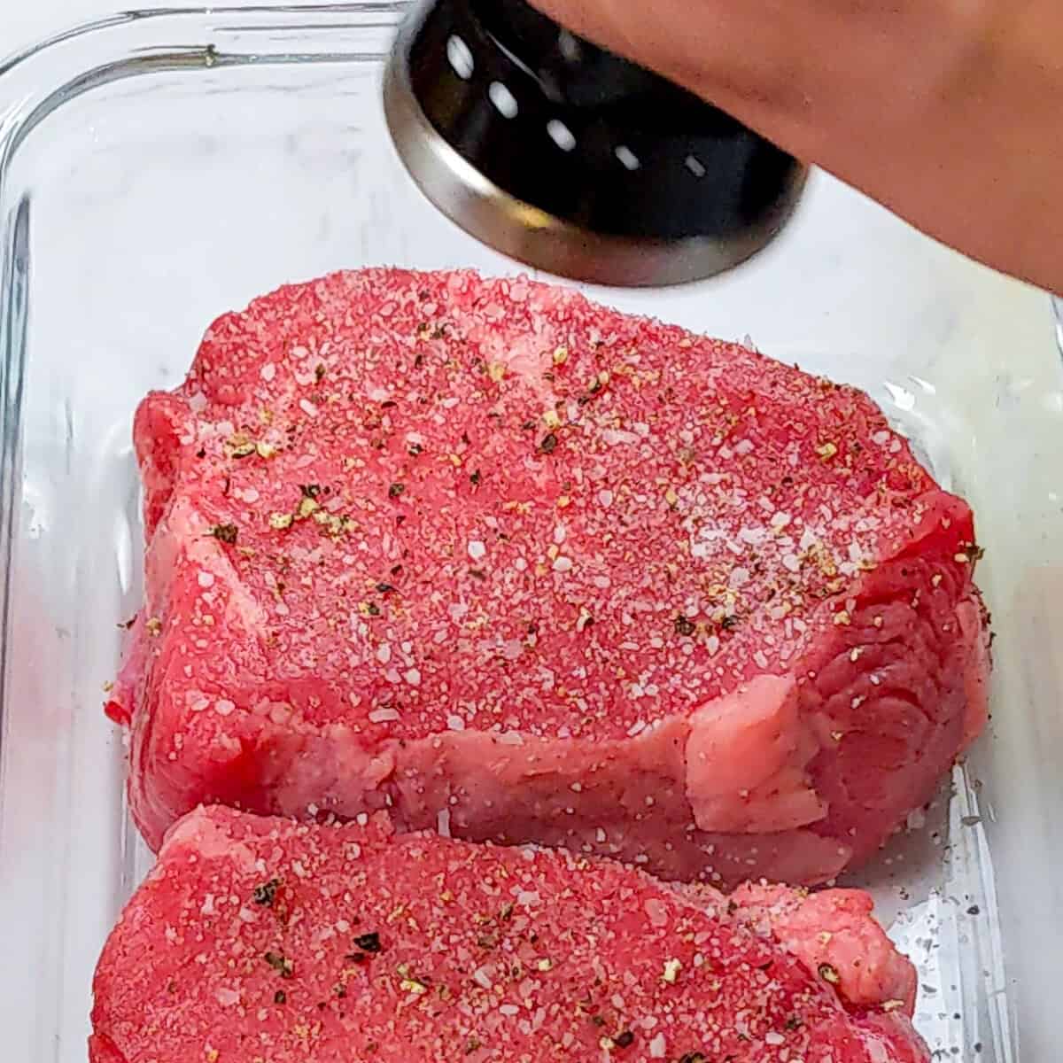 Seasoning thick top sirloin steaks for a flavorful, mouthwatering meal in a clean kitchen.