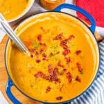 Vibrant spicy bacon potato leek chowder served in a cobalt blue pot, perfect for comfort food.