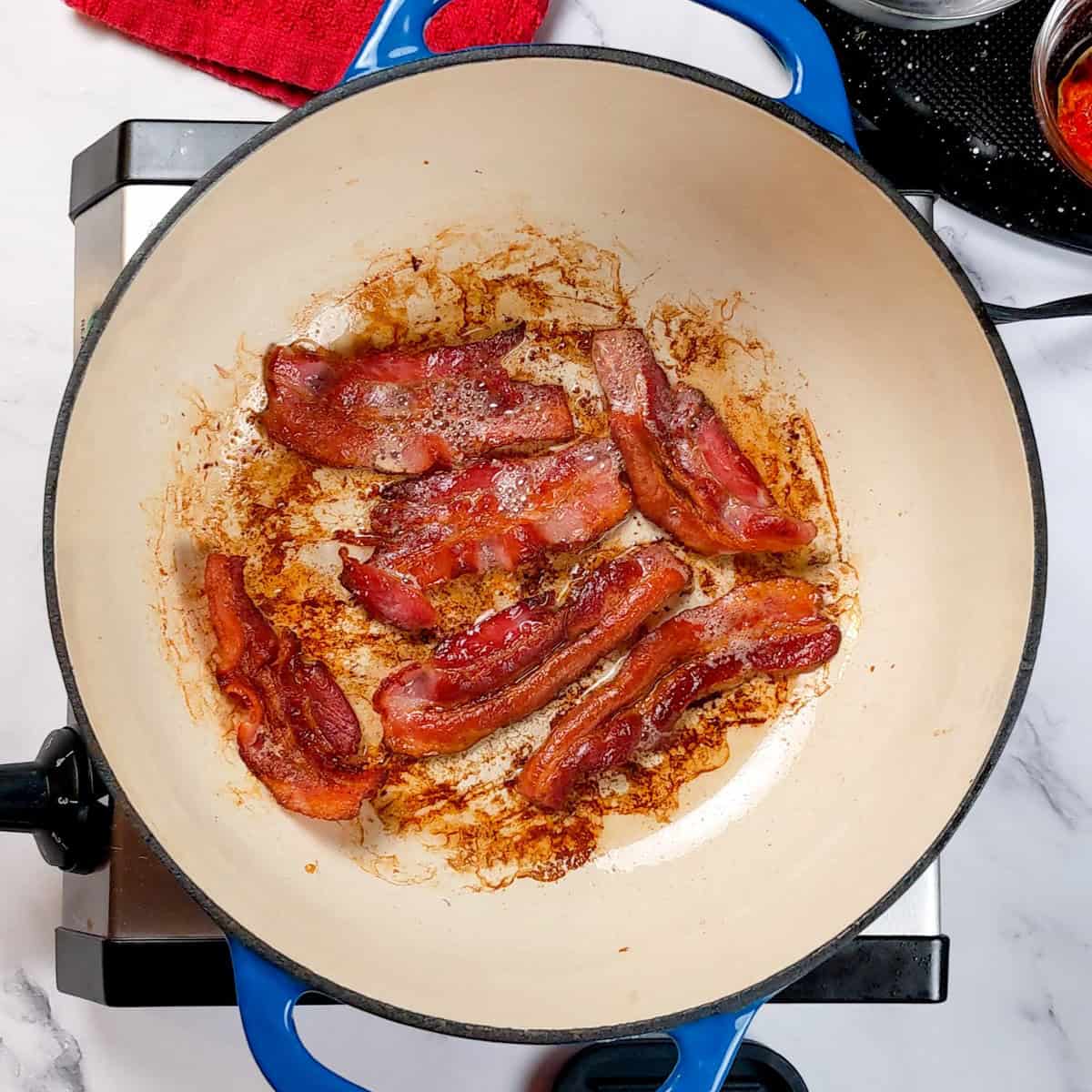 Crispy bacon frying in a colorful skillet, perfect for hearty chowder recipes.