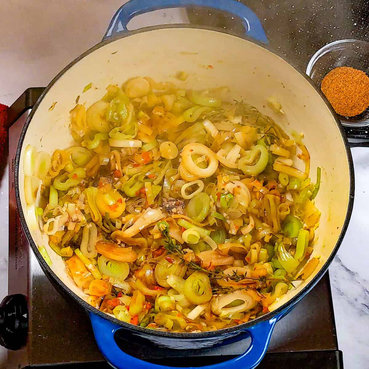 Vibrant sautéed leeks and vegetables in a blue Dutch oven, perfect for chowder.