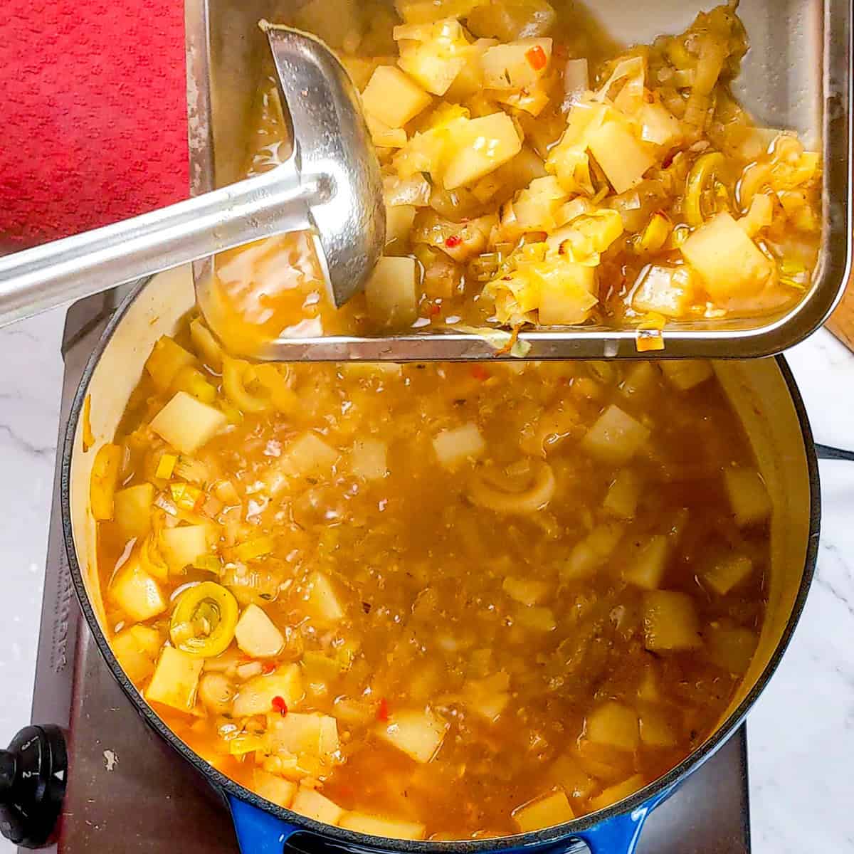 Pouring ingredients into a pot of spicy bacon potato leek chowder in a cozy kitchen.