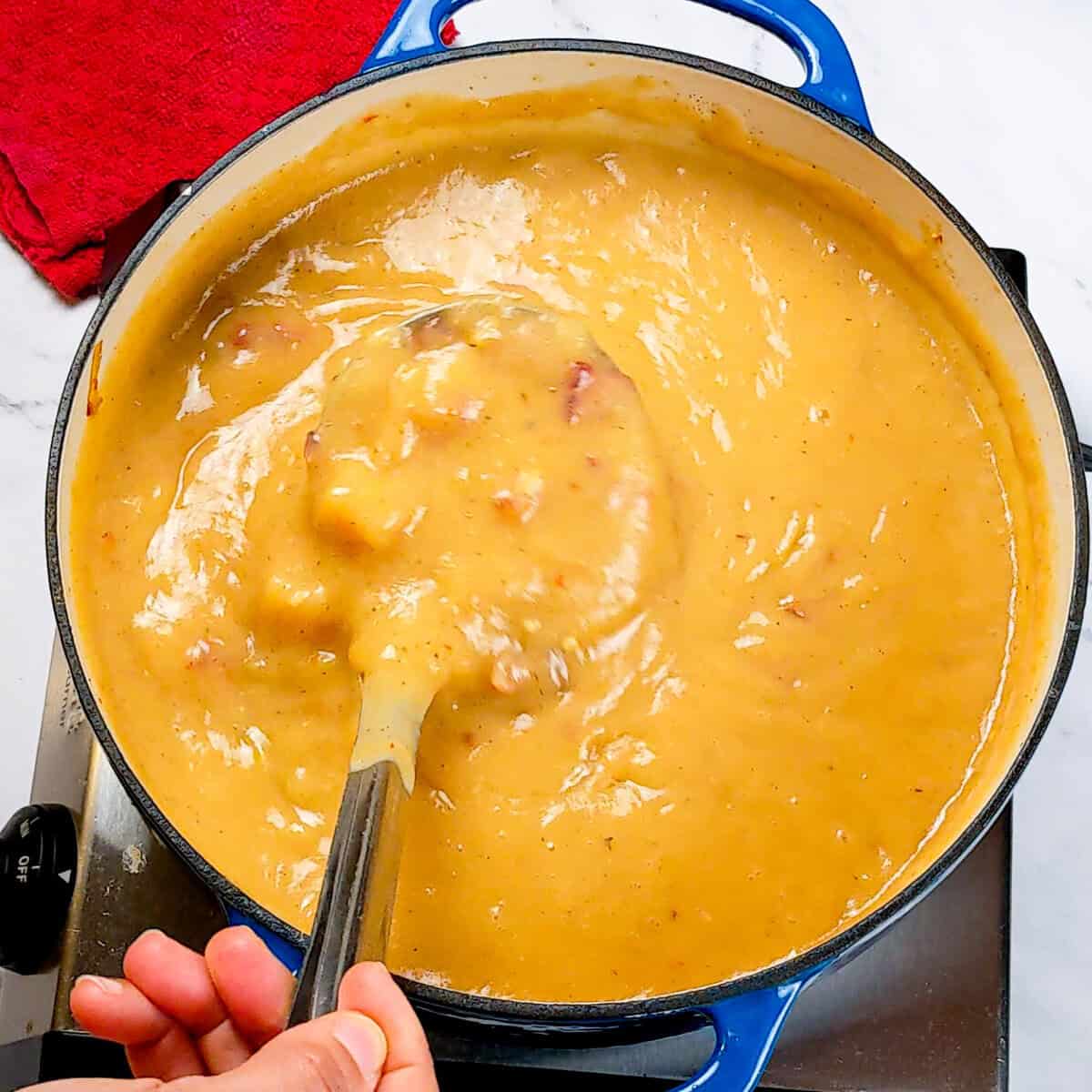 Vibrant bowl of spicy bacon potato leek chowder simmering on the stovetop, ready to serve.