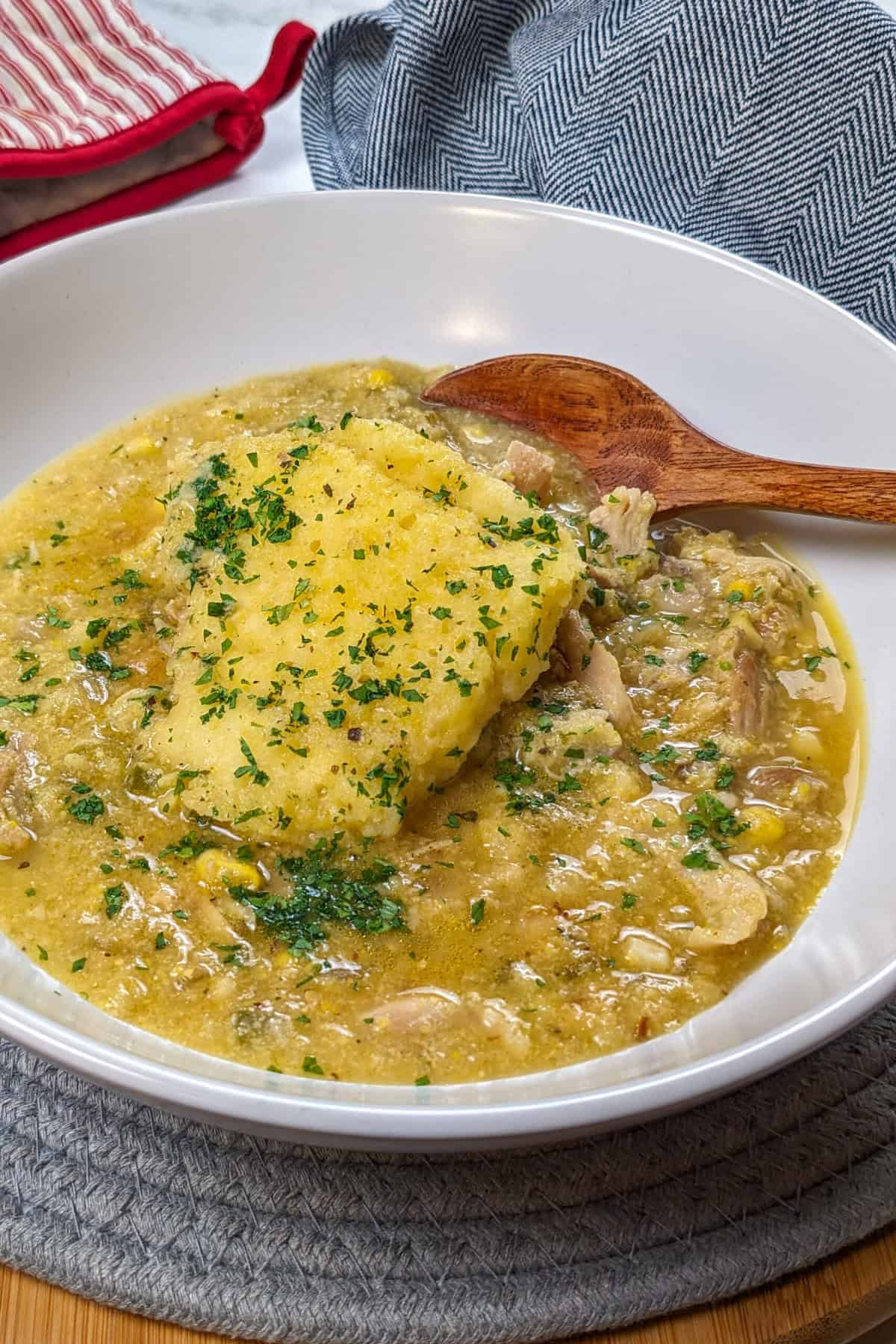 Hearty chicken corn chowder with fluffy dumplings, fresh herbs, and a cozy kitchen backdrop.