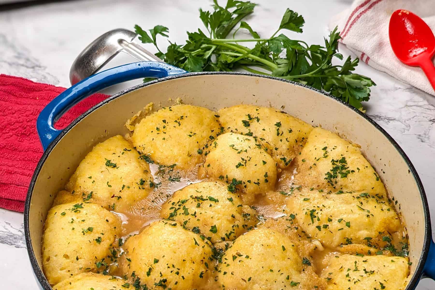 Golden chicken corn chowder dumplings simmer in flavorful broth, garnished with fresh parsley.