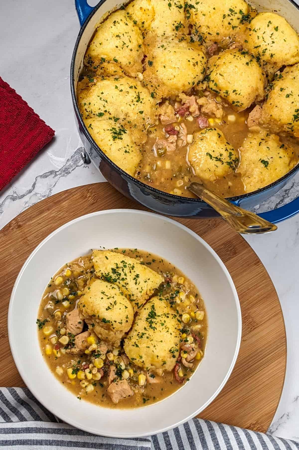 Hearty chicken corn chowder topped with fluffy dumplings garnished with fresh herbs.