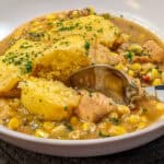 Hearty chicken corn chowder topped with fluffy cornbread dumplings and fresh parsley garnish.