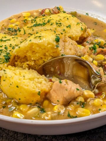 Hearty chicken corn chowder topped with fluffy cornbread dumplings and fresh parsley garnish.