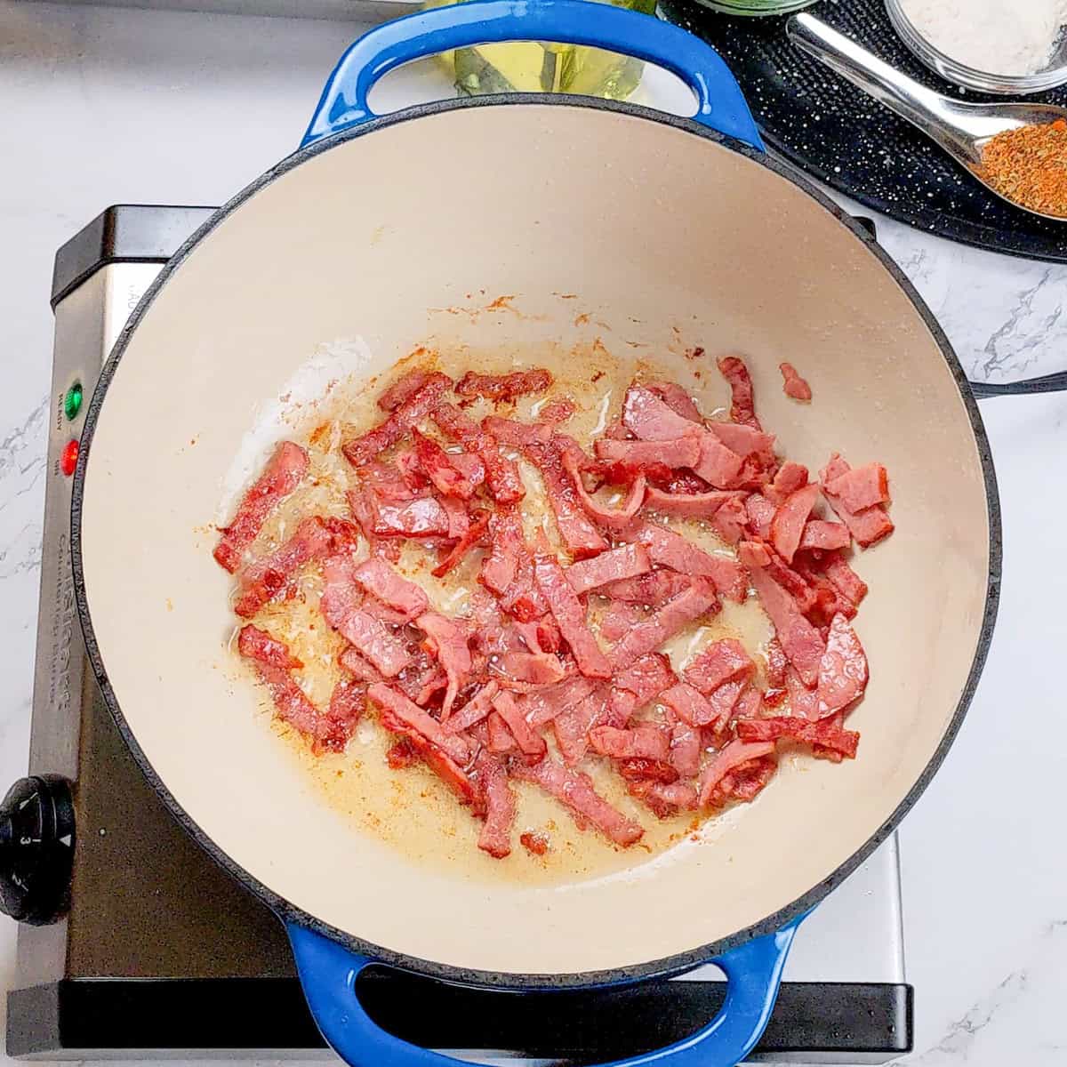 Bacon sizzling in a blue enamel pot, perfect for chicken corn chowder dumplings.