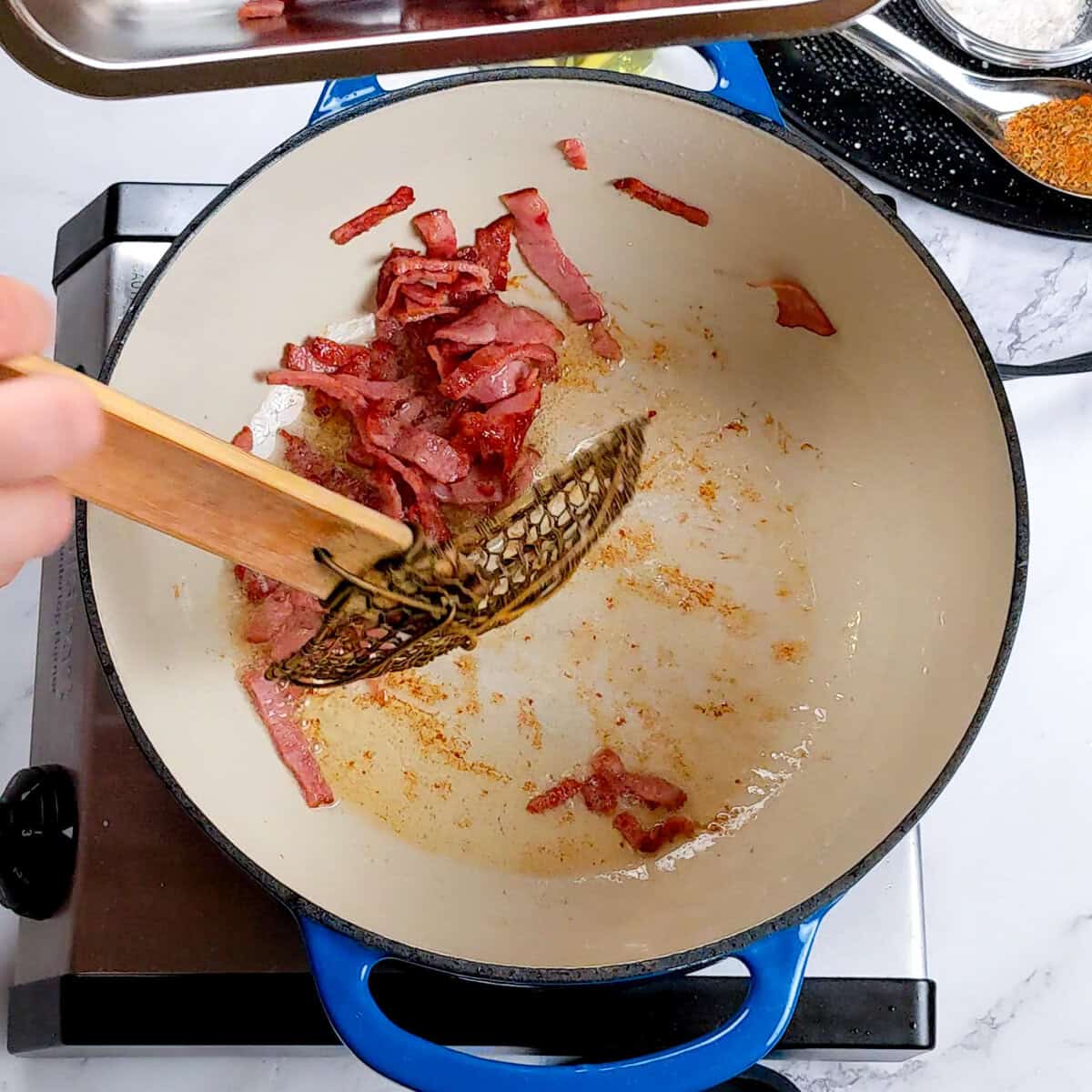 Cooking chicken corn chowder dumplings in a vibrant Dutch oven on a marble countertop.