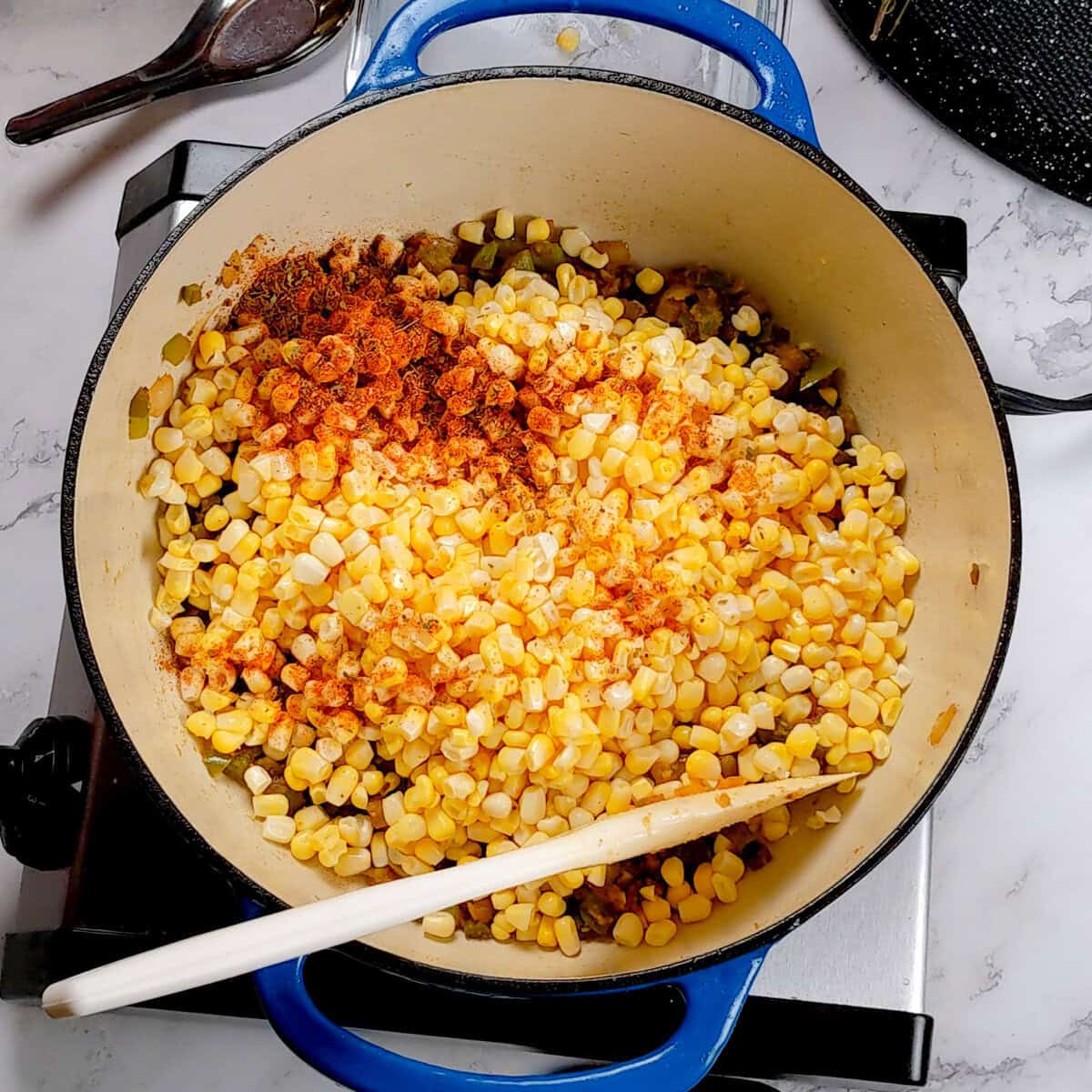 Fresh sweetcorn with spices in a blue pot, perfect for Chicken Corn Chowder Dumplings.