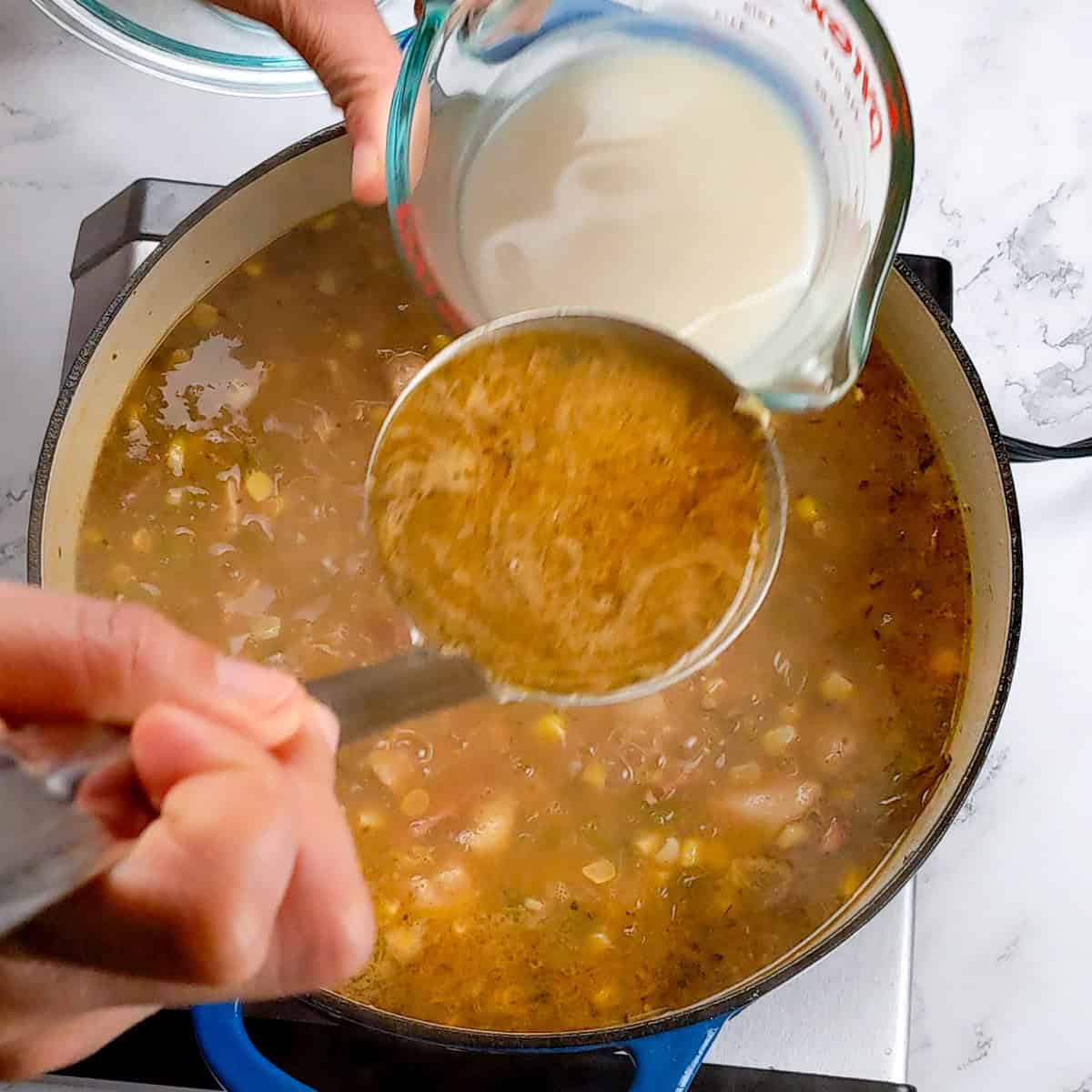 Creamy chicken corn chowder being ladled from a pot, enhancing flavors with added oat milk.