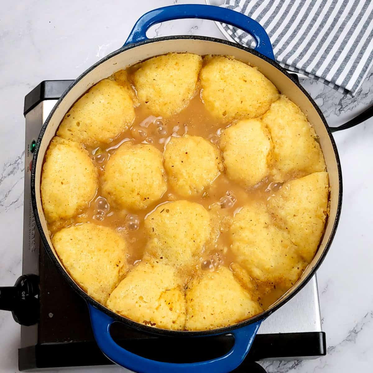 Savory chicken corn chowder dumplings simmering in a vibrant blue pot, evoking comfort food warmth.