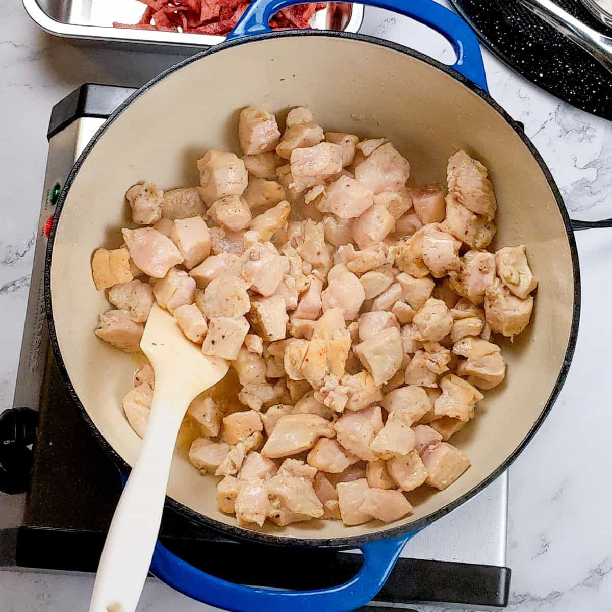 Dutch oven with cooked diced chicken.