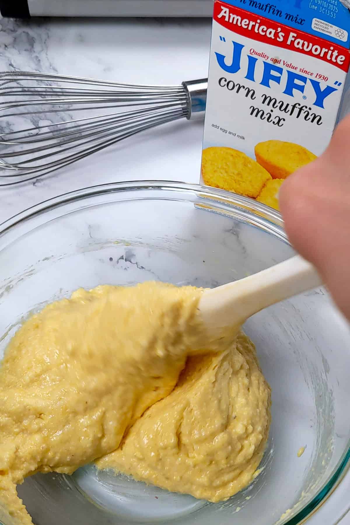 Mixing Jiffy corn muffin batter in a clean kitchen with vibrant ingredients for homemade baking.