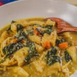 Homemade curry coconut chicken gnocchi soup with colorful vegetables and herbs.