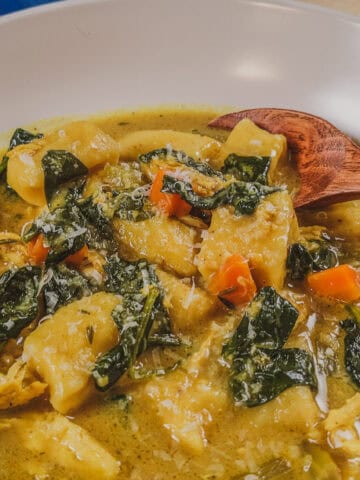 Homemade curry coconut chicken gnocchi soup with colorful vegetables and herbs.