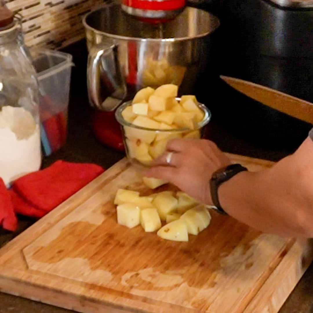 Chopping potatoes for curry coconut chicken gnocchi soup in a cozy kitchen setting.