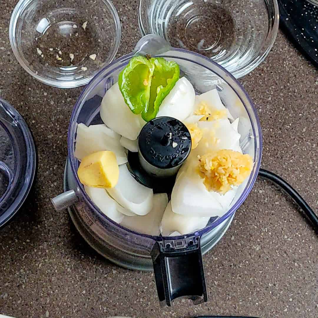 Fresh ingredients in a food processor for Curry Coconut Chicken Gnocchi Soup preparation.