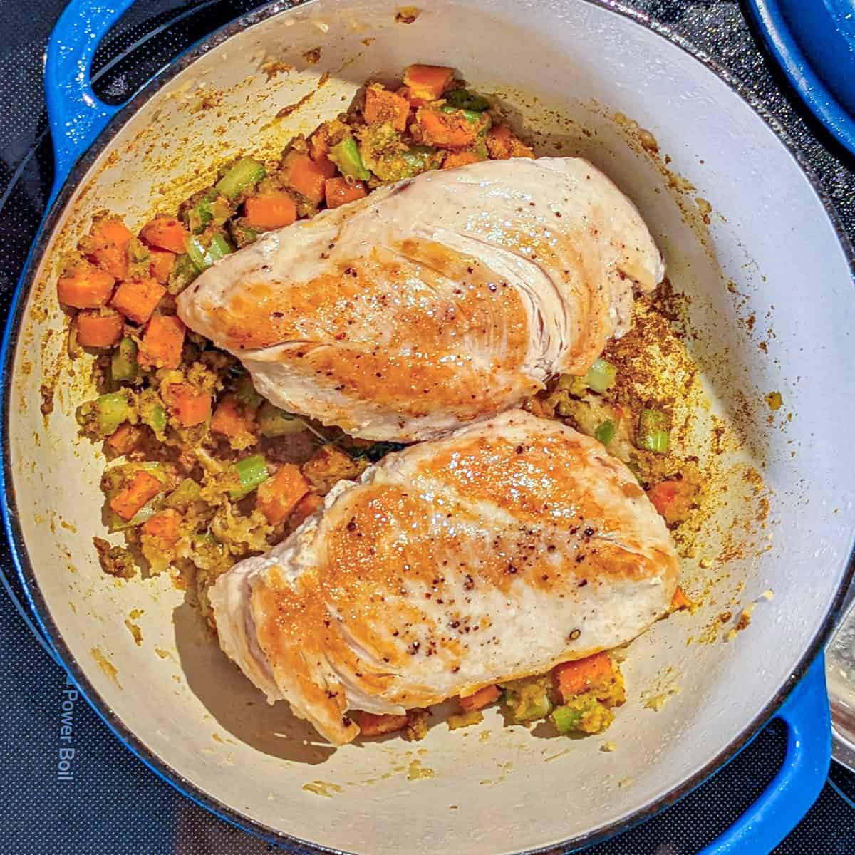 Golden brown chicken breasts and sautéed vegetables in a vibrant Dutch oven.