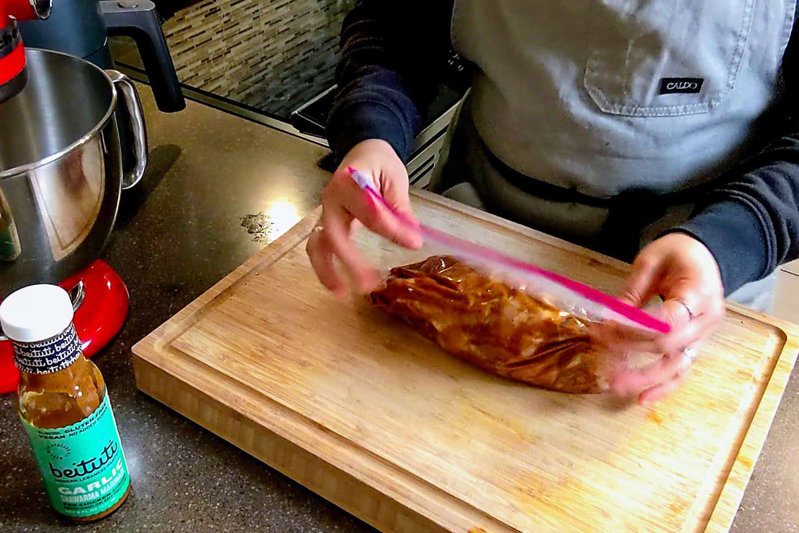 massaged marinated chicken being sealed in a zip top bag.