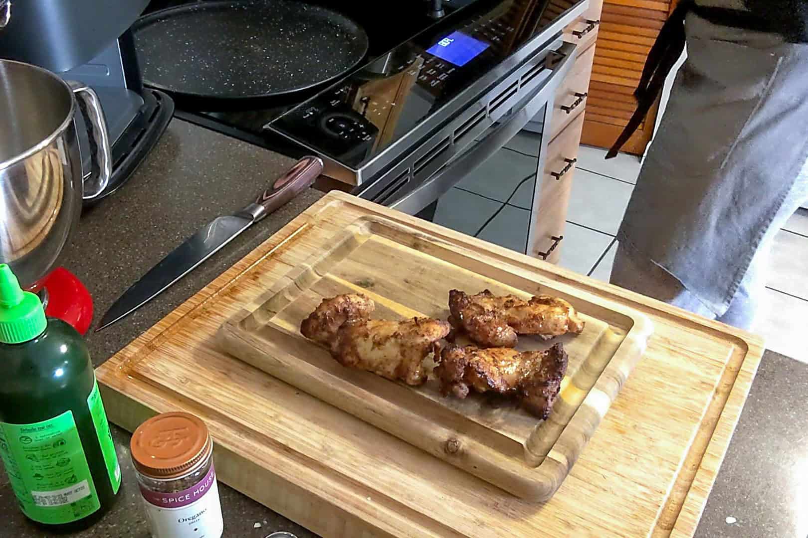 cooked golden brown chicken thighs on a cutting board resting.