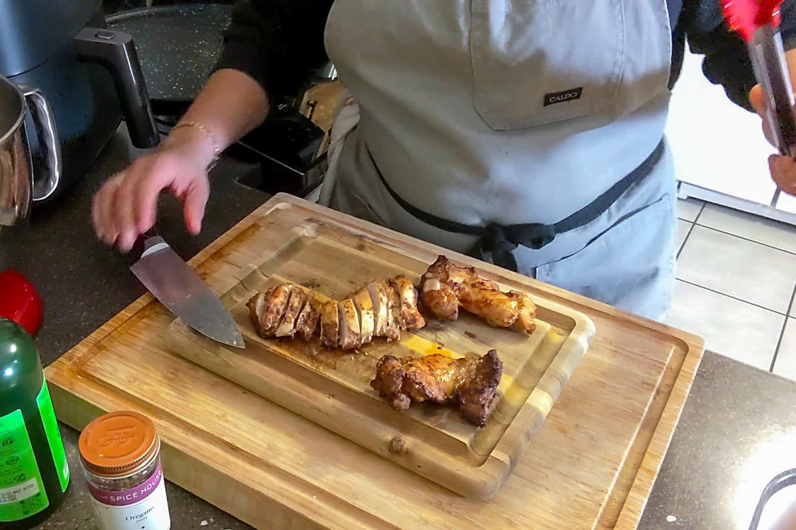 sliced cooked boneless skinless marinated chicken thighs on a cutting board.