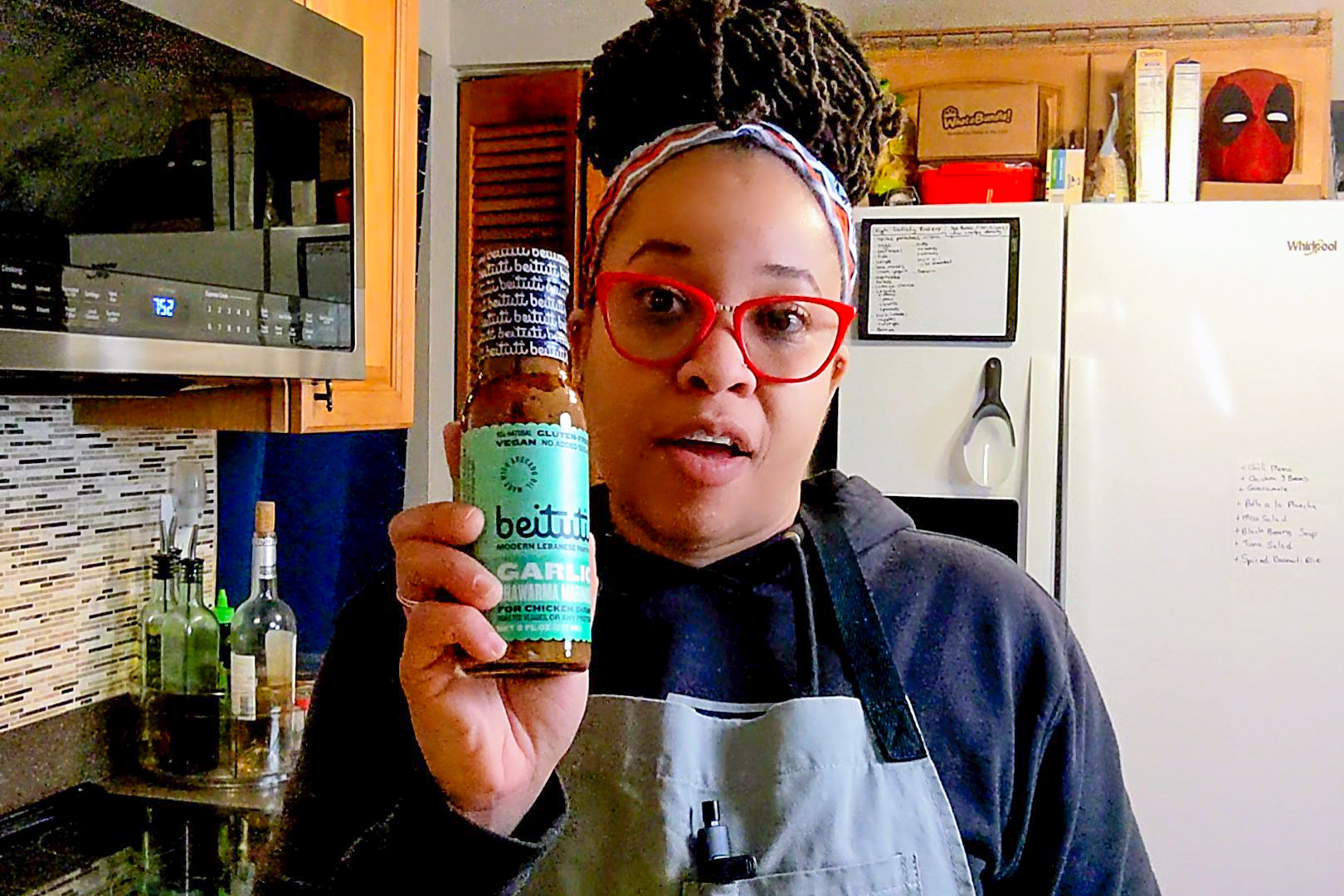 chef maika showcasing the unopened beituti garlic shawarma marinade bottle in her hand.