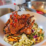 Habanero tamarind glazed chicken wings served over fresh vegetable salad in a vibrant bowl.