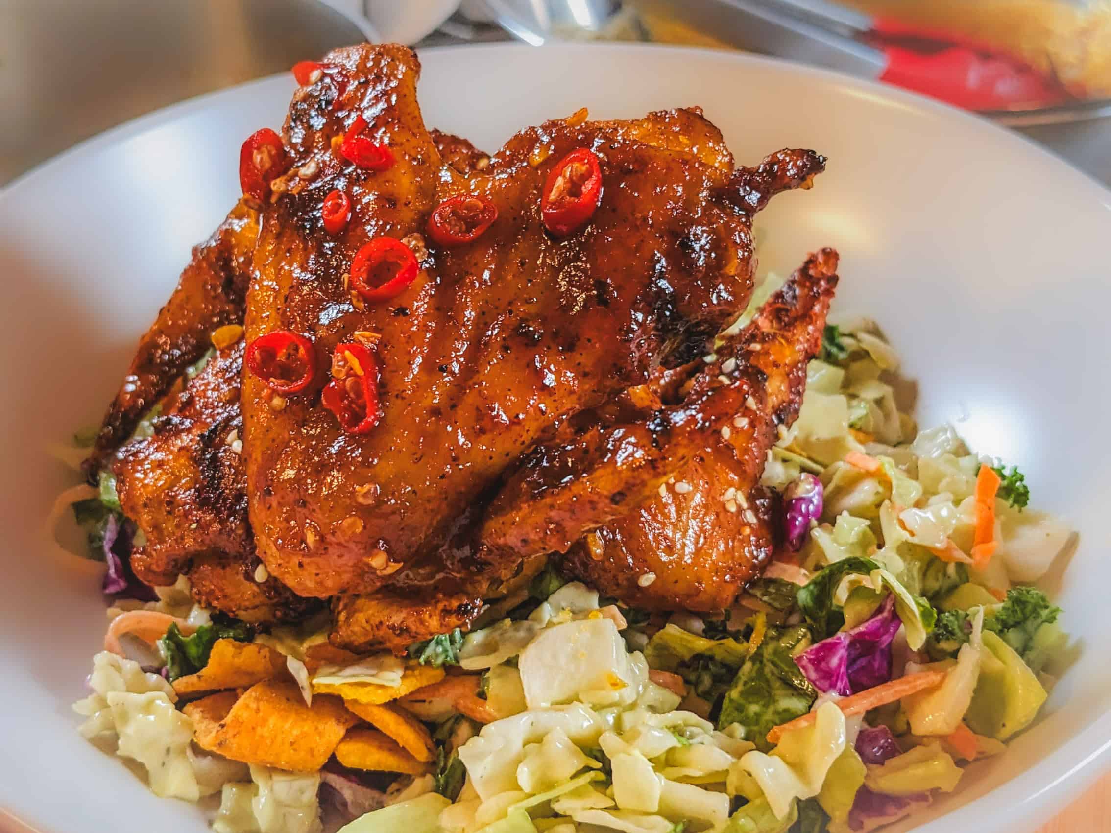 Habanero tamarind glazed chicken wings atop a vibrant salad of crunchy vegetables.