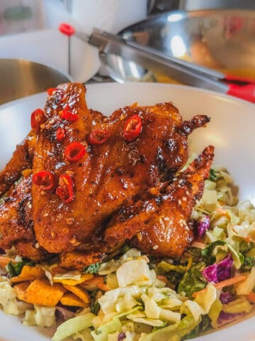 Habanero tamarind glazed chicken wings served over fresh vegetable salad in a vibrant bowl.