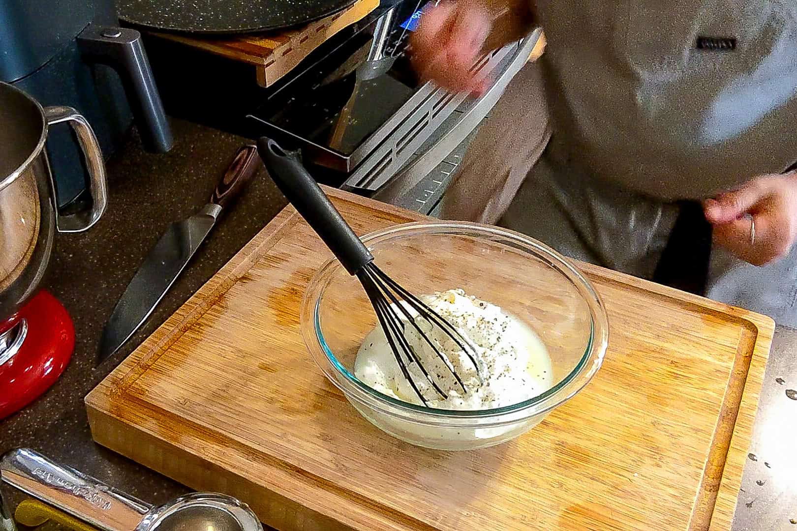 greek yogurt, lemon juice and herbs in a glass bowl with a whisk.