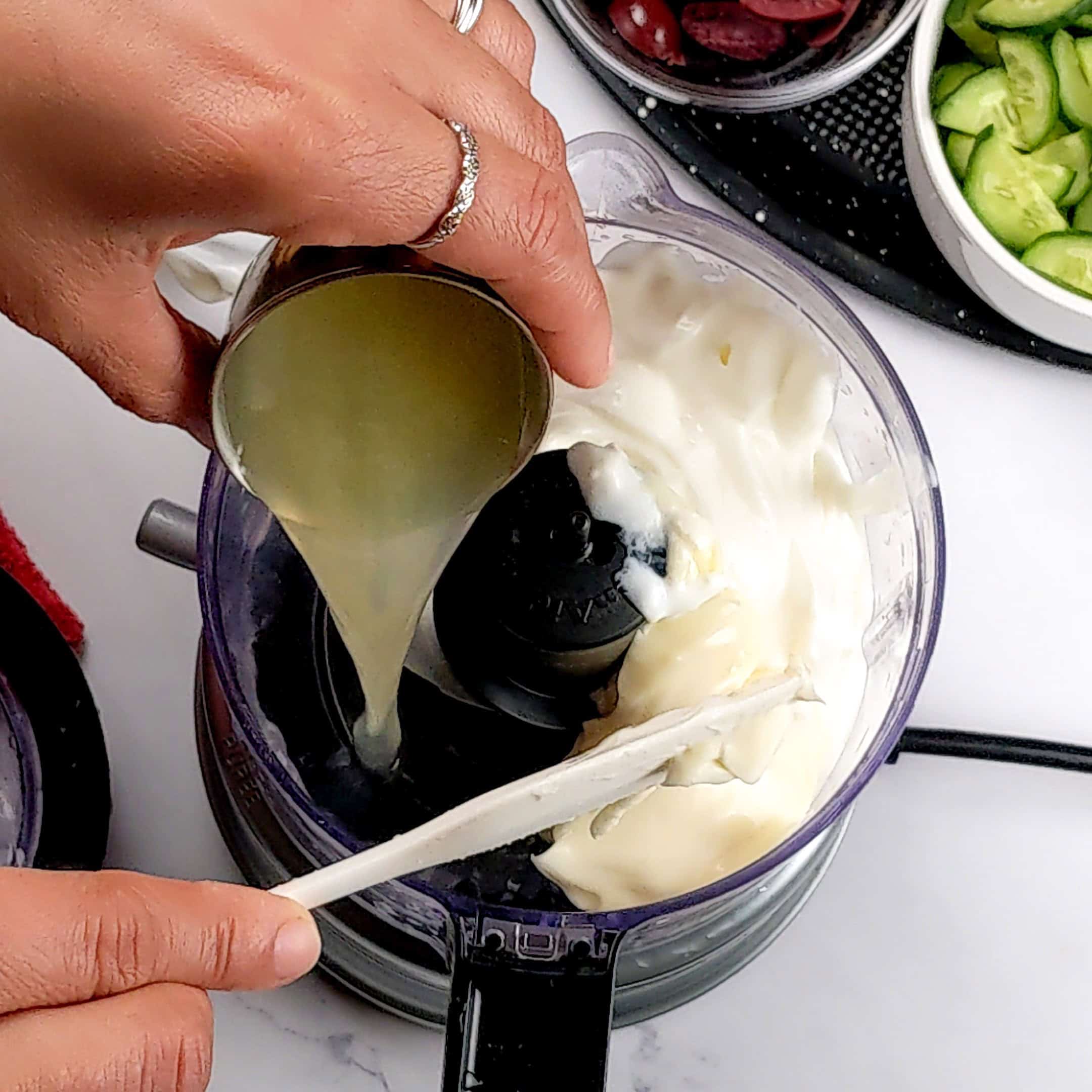 lemon juice being added to greek yogurt in the food processor.