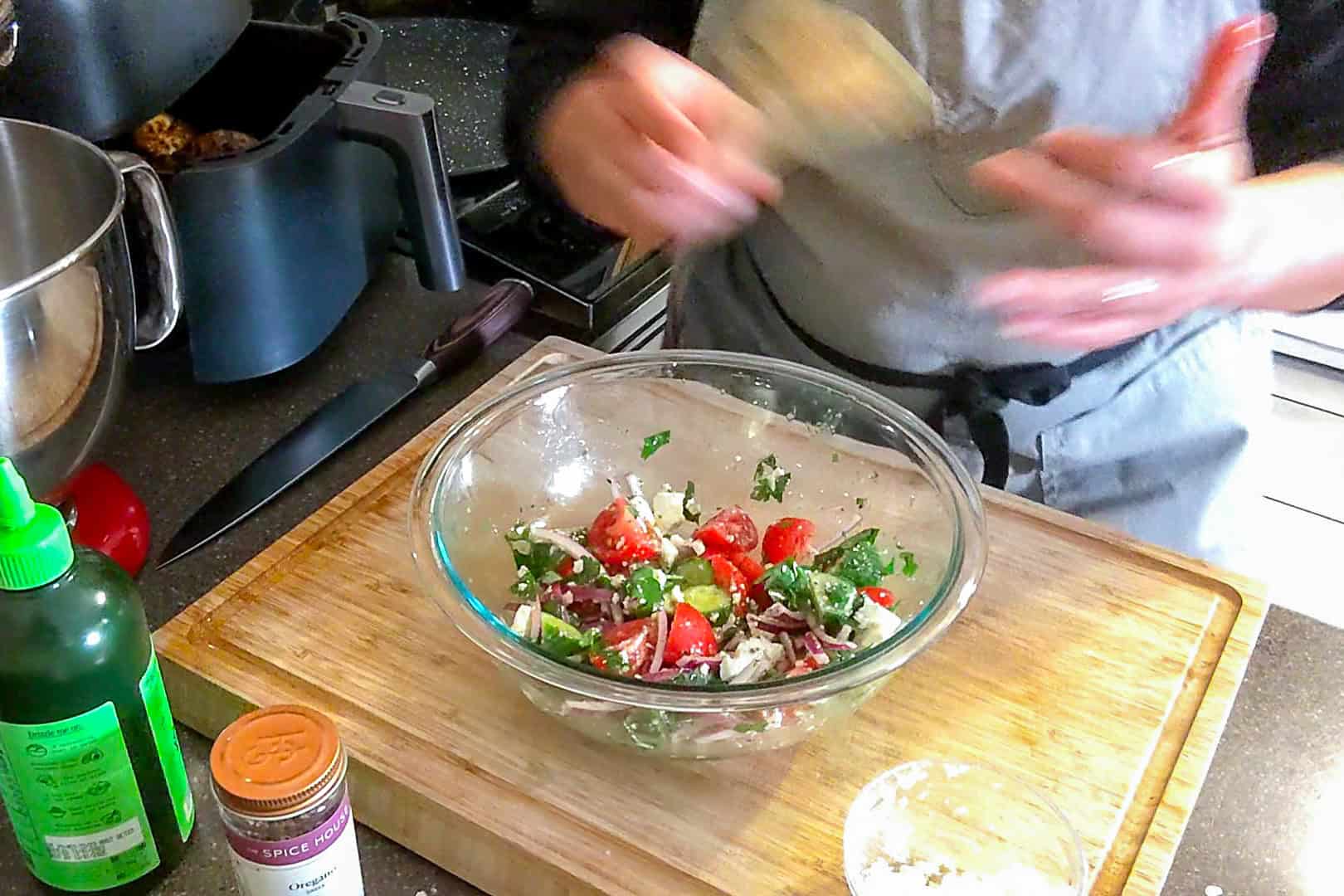 chef maika with a bowl of the Parsley Cucumber Tomato Feta Salad on a cutting board.