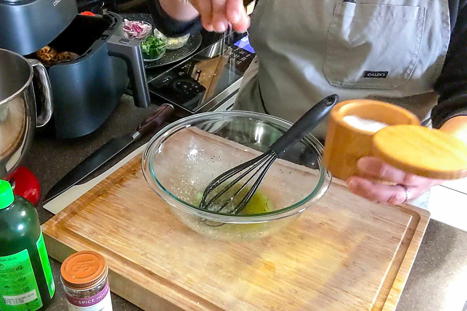 chef maika adding salt to the whisked salad dressing.