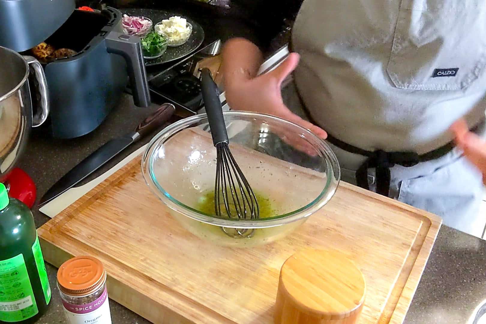 vinaigrette in a glass mixing bowl with a silicone whisk.