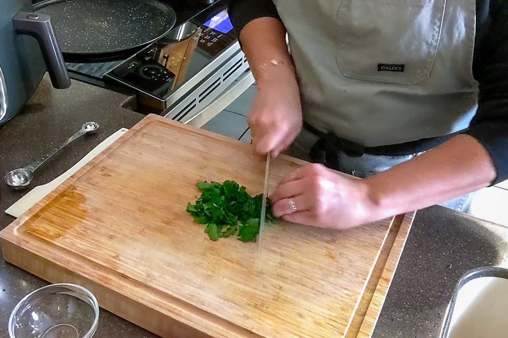 parsley leaves being chopped on a cutting board.