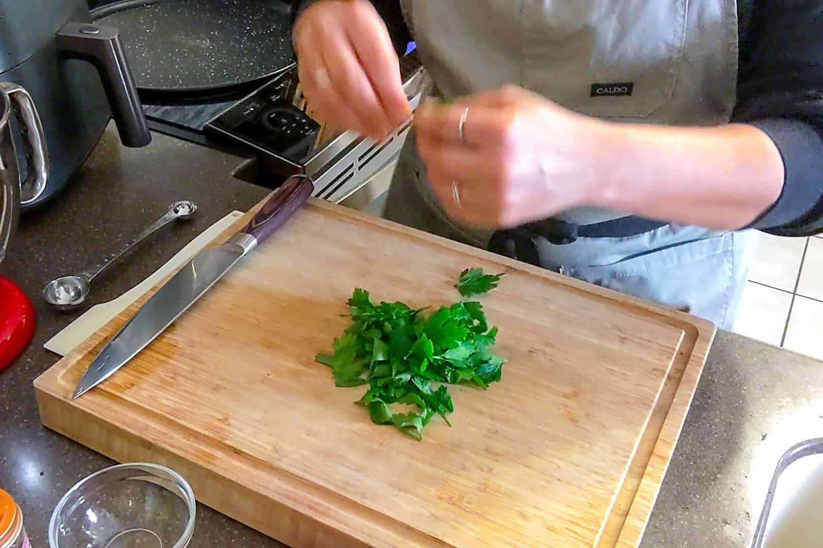 prepping parsley leaves to chop on a cutting board.