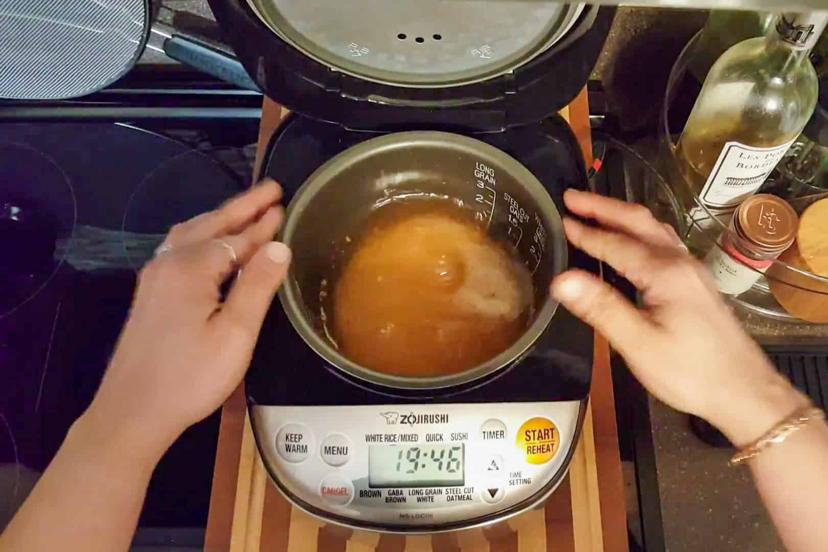 seasoned and water filled rice insert being placed in the Zojirushi rice cooker.