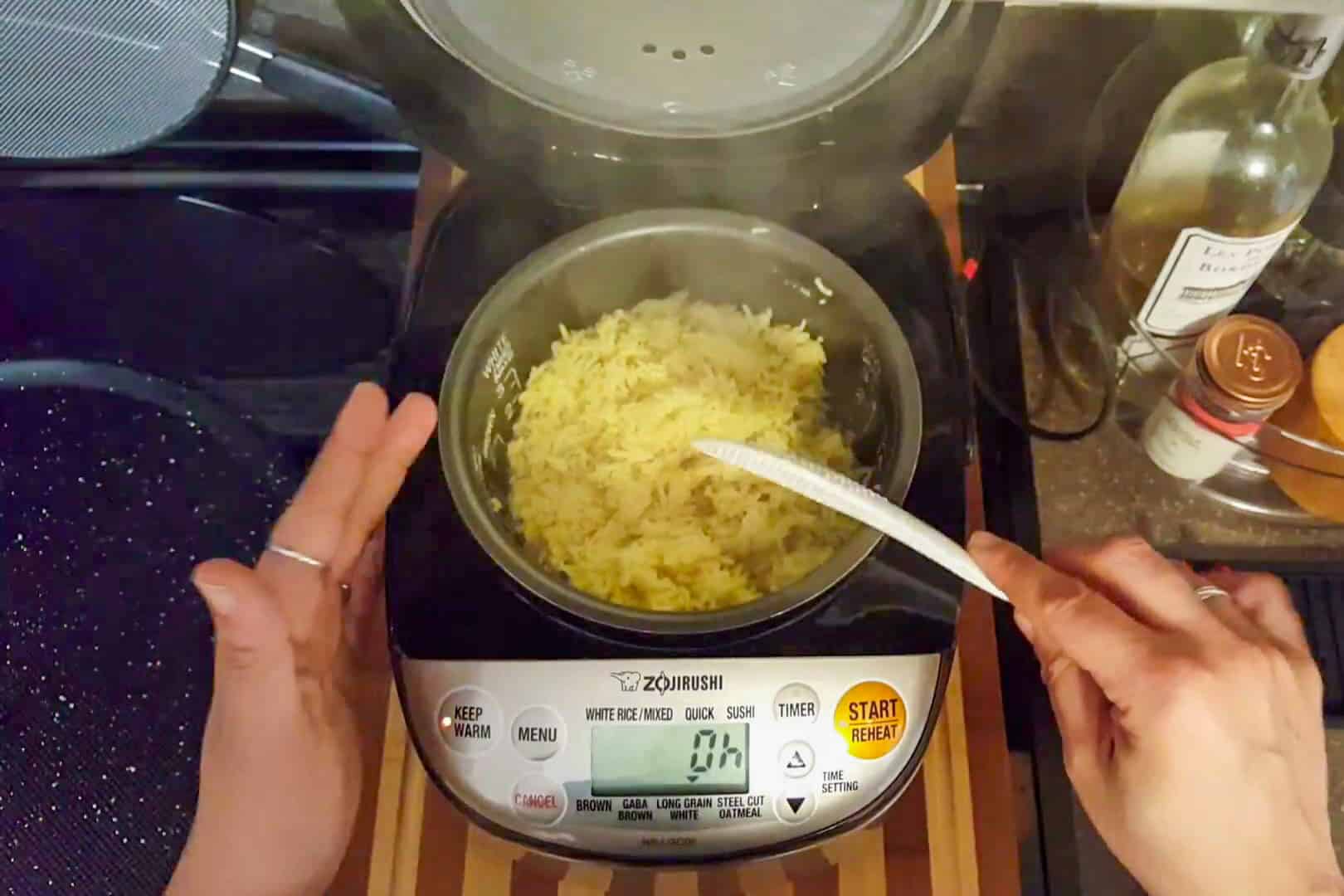 fluffing rice in the rice cooker with a rice paddle.