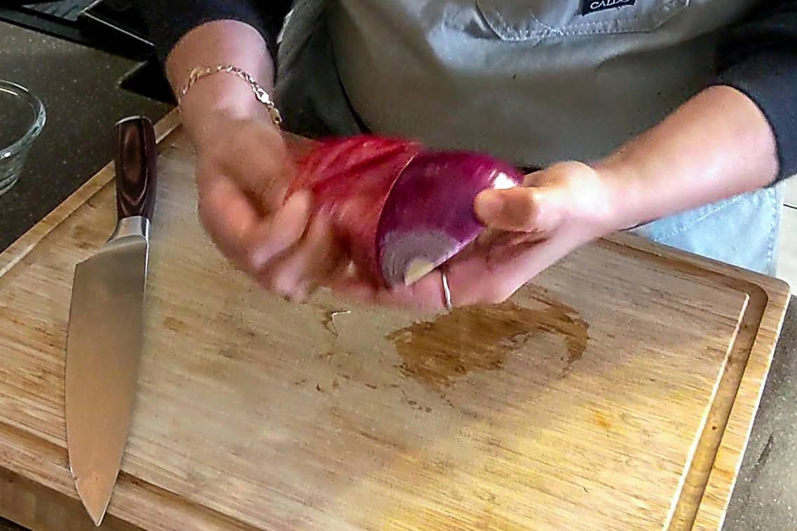 peeling the cut red onion.