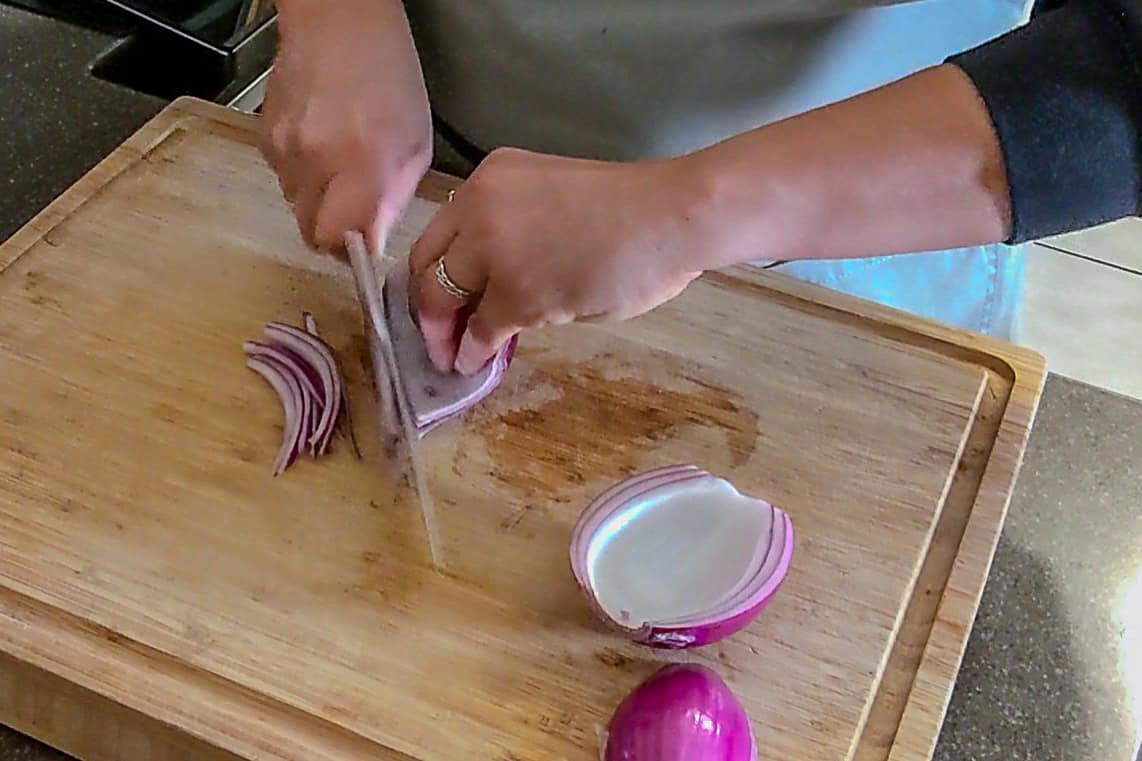 slicing the red onion while faced up.