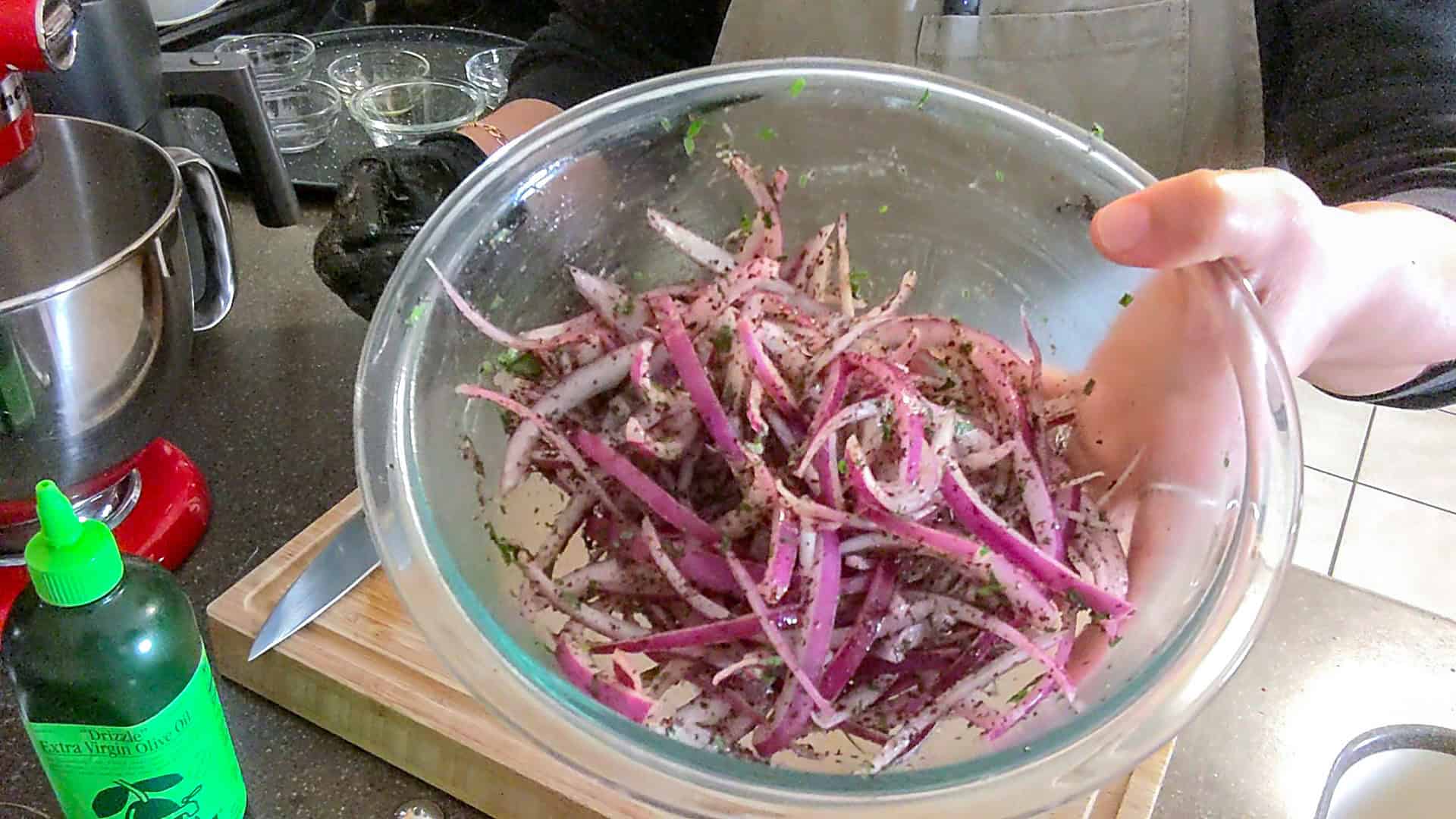 up close shot of the sumac onions in a glass mixing bowl..