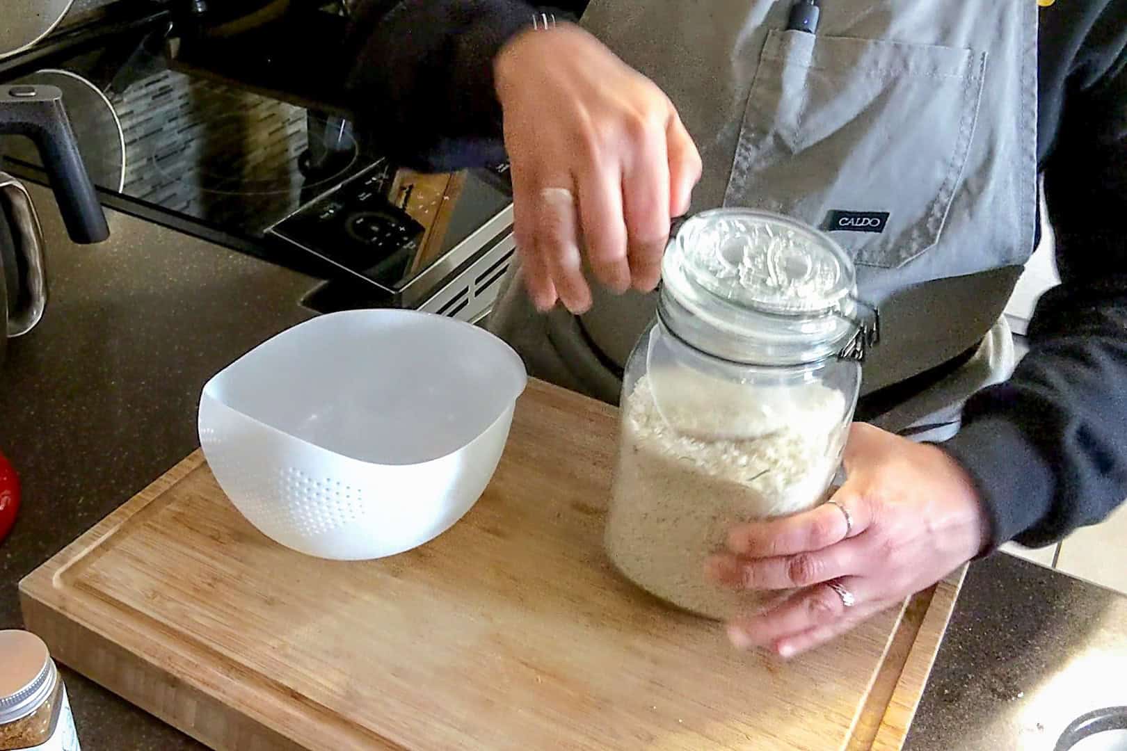 chef maika opening a glass storage canister of rice.