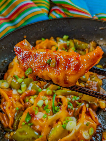 pan seared dumplings on chopsticks to show the golden brown bottom.