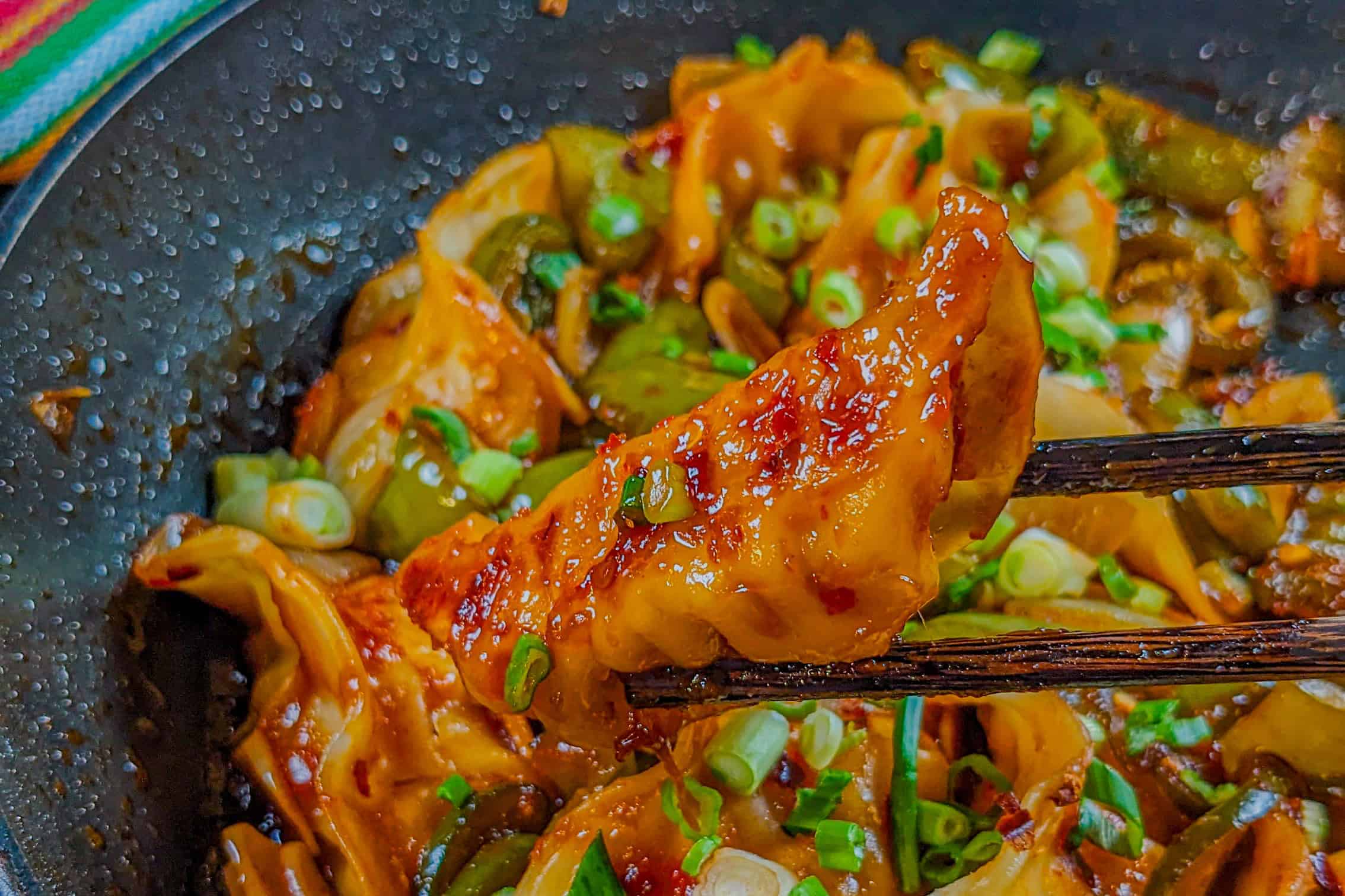 pan seared dumplings on chopsticks to show the golden brown bottom.