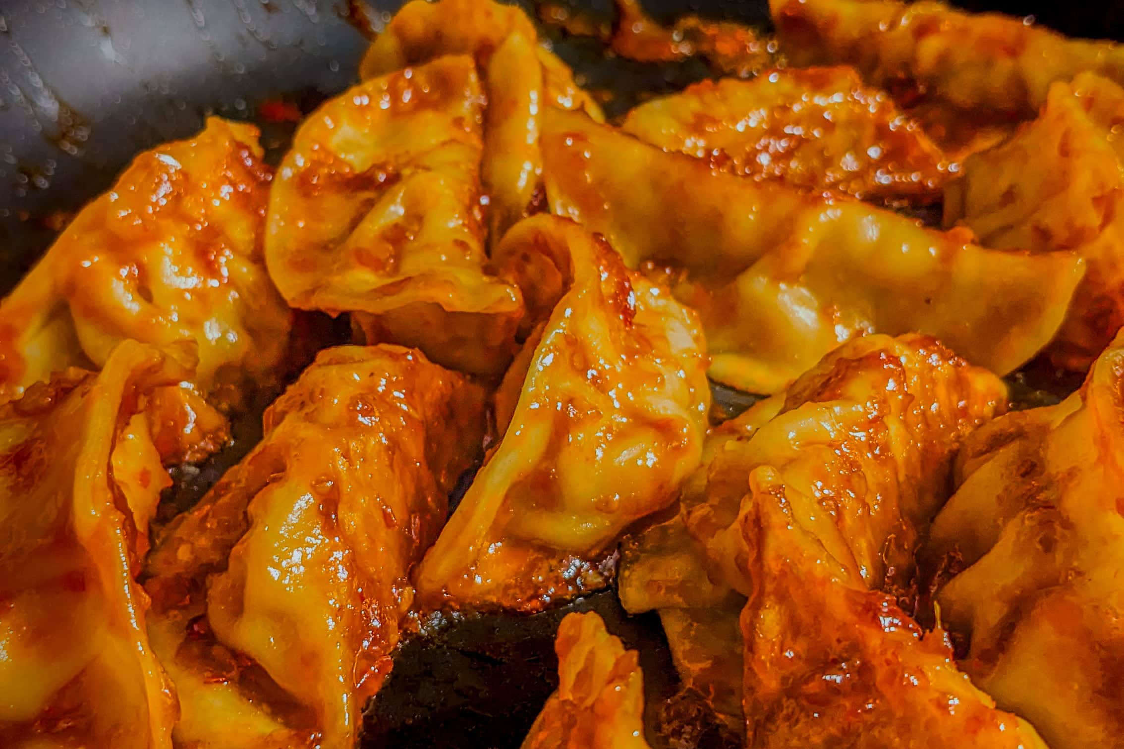 potstickers with no vegetables covered in Chef Maika's Chili Momo style sauce in a nonstick saute pan.