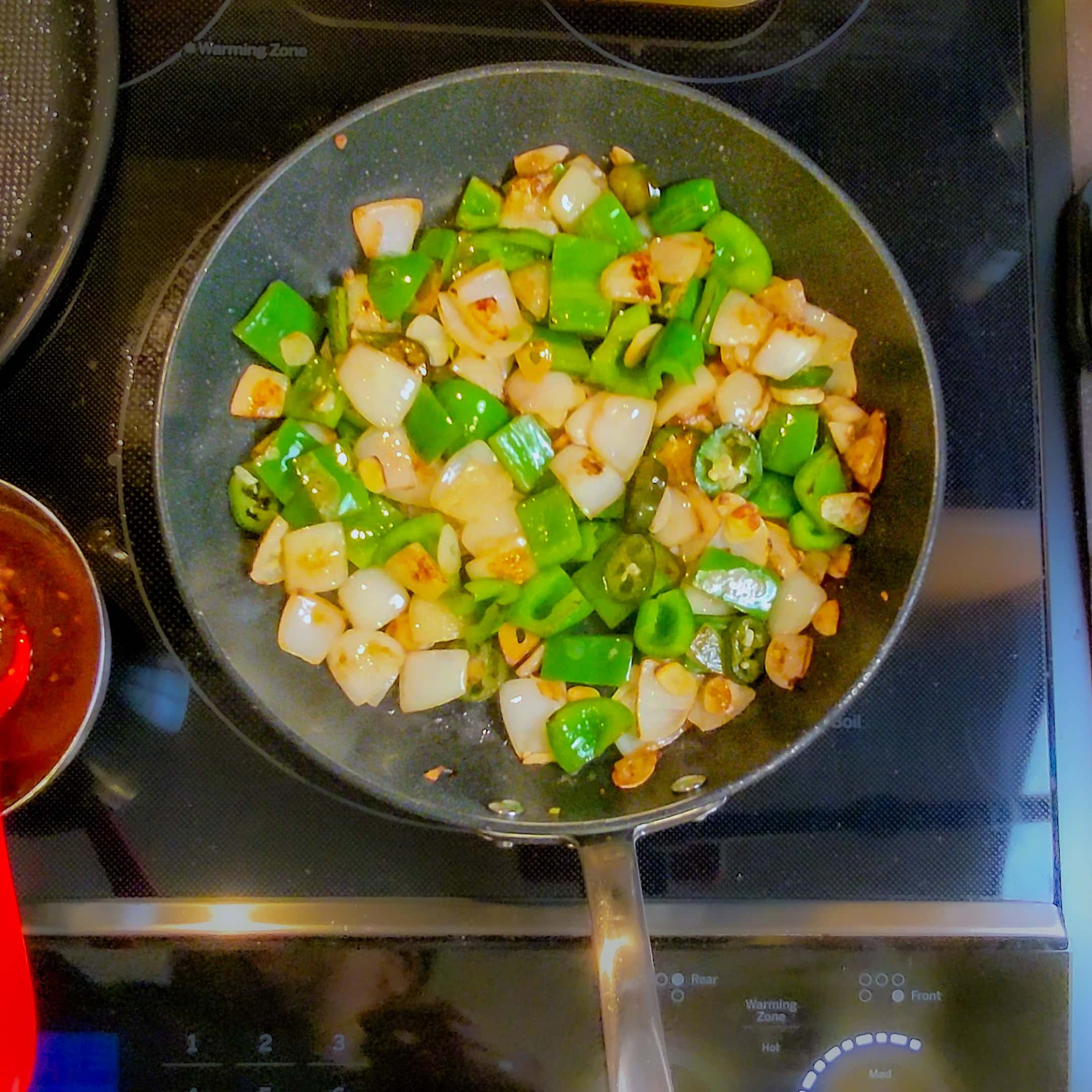 top view of sauted large diced green bell pepper, onion and sliced jalapeno.