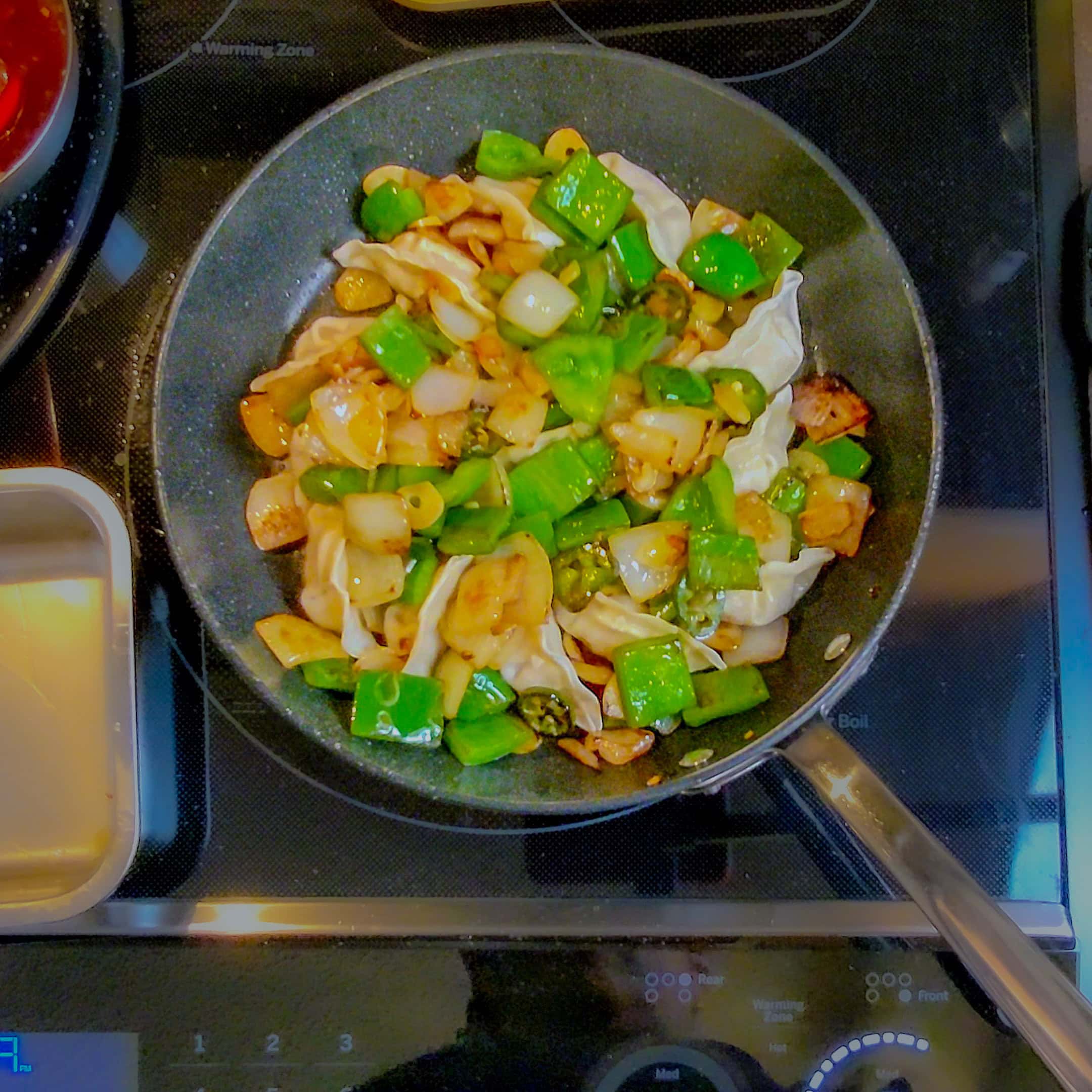 top view of caramalized sauted large diced green bell pepper, onion and sliced jalapeno for chili momo.